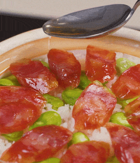 大米出現(xiàn)小孔時開蓋放香腸，往鍋邊淋入少許油，再燜煮8~10分鐘左右。