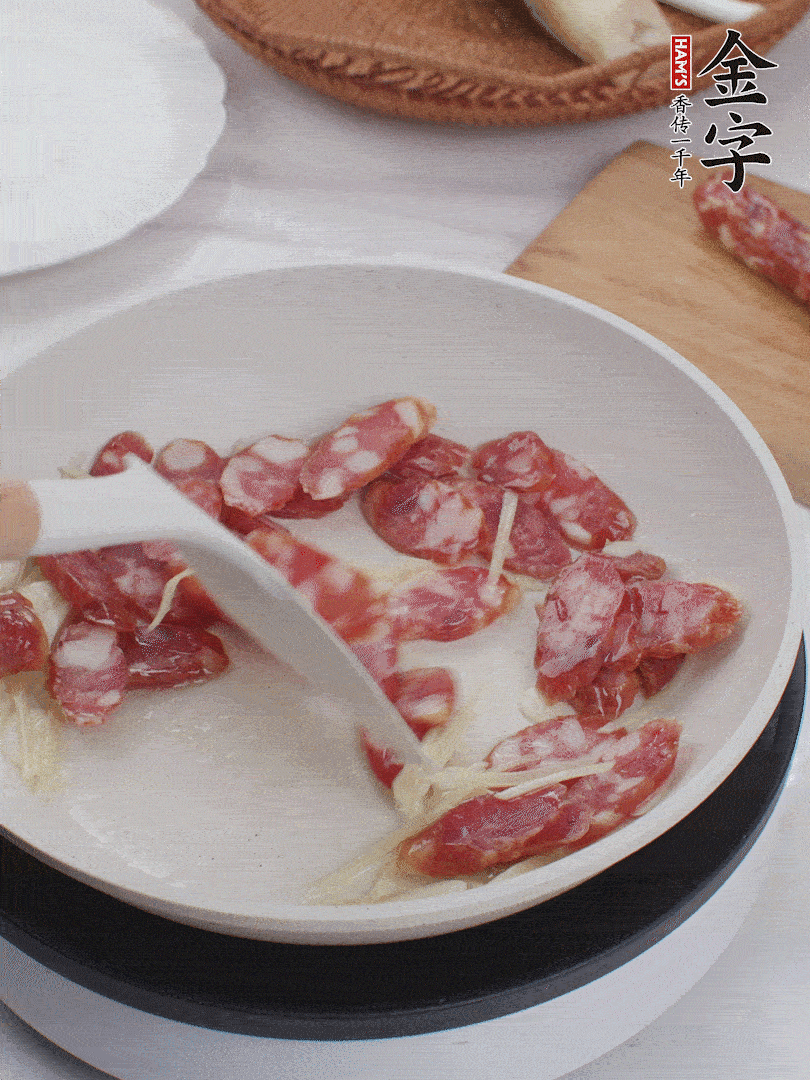 油溫3成熱時(shí)，下姜絲、蒜片、香腸炒出油脂。