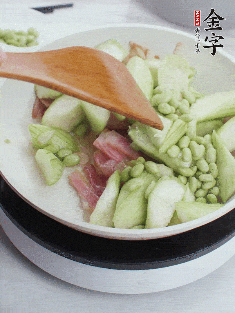 依次下絲瓜、青豆翻炒，炒至絲瓜打蔫縮小。