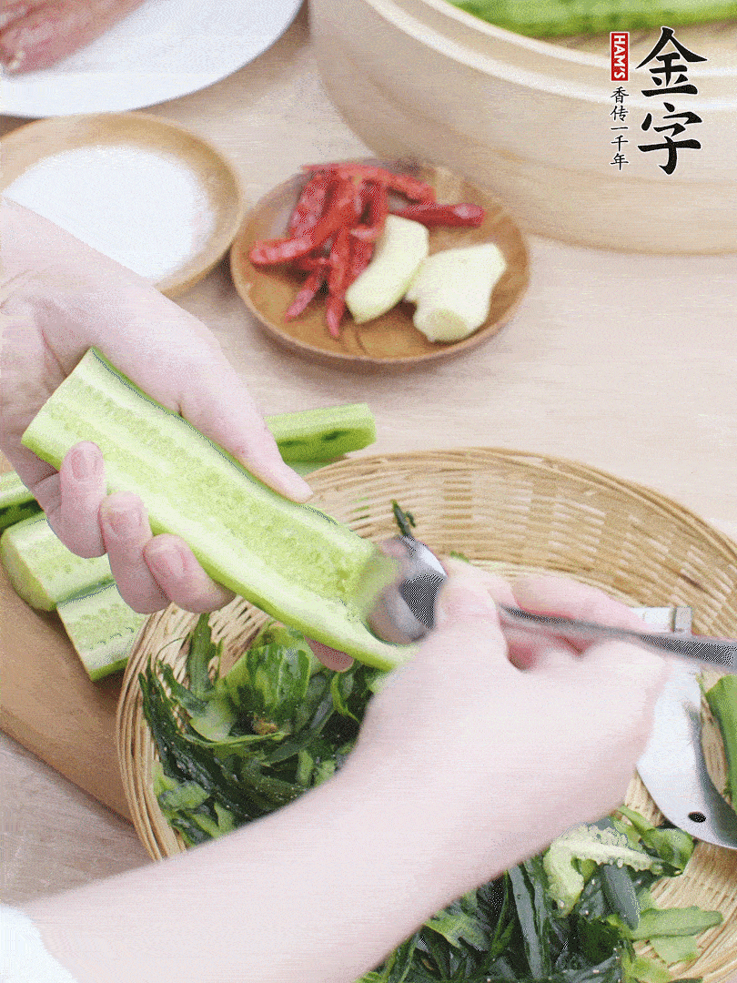 黃瓜削皮，對半切開，勺子挖去內(nèi)瓤，斜刀切片。青蒜斜刀切段。