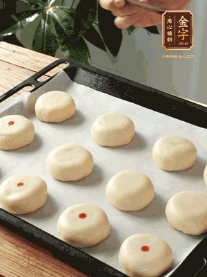 收口向下放在案板上，輕輕將月餅坯按扁，用筷子點紅點做裝飾